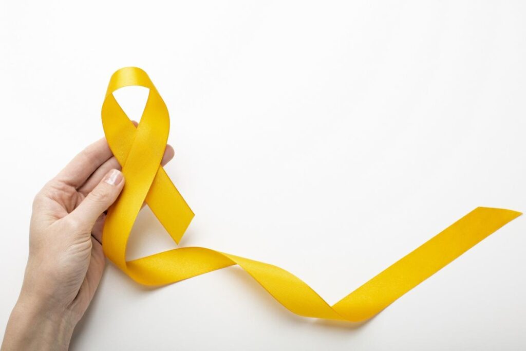 mão branca segurando o laço amarelo, simbolizando o julho amarelo: mês de conscientização sobre as hepatites virais