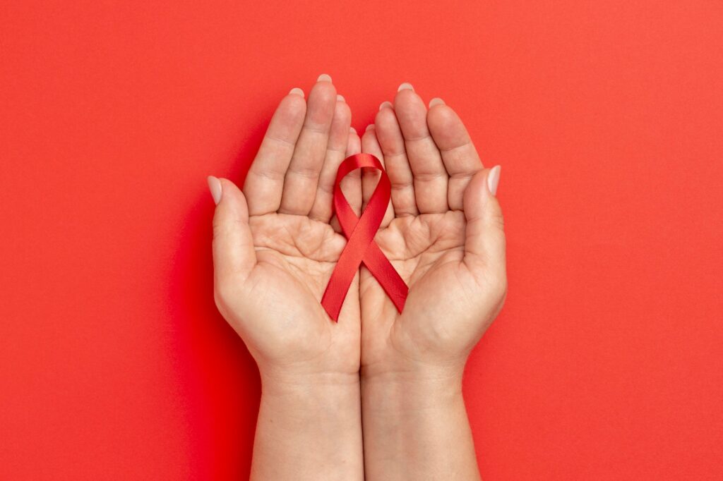 mão segurando uma fita vermelha, representando o mês de conscientização sobre a saúde cardiovascular