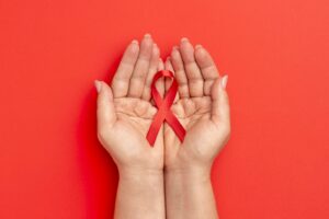 mão segurando uma fita vermelha, representando o mês de conscientização sobre a saúde cardiovascular
